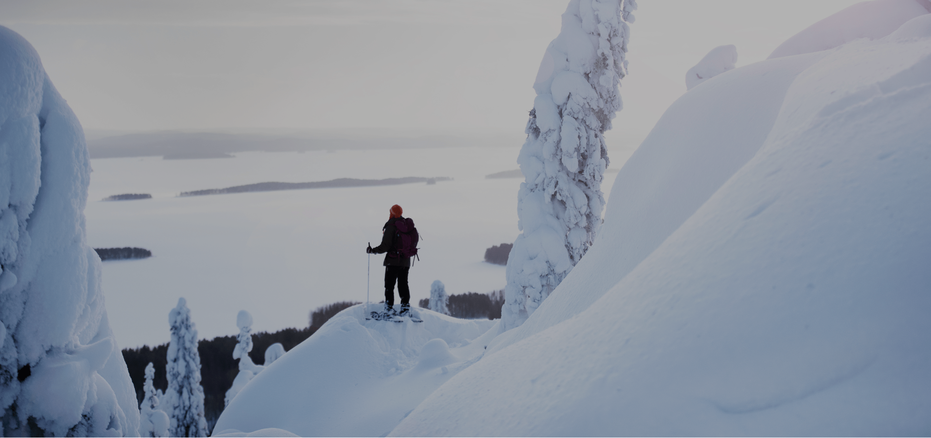 A person hiking in a snow-covered landscape with a backpack in North Karelia, Finland, featured in the Visit Karelia platform case study on Russia-Promo.