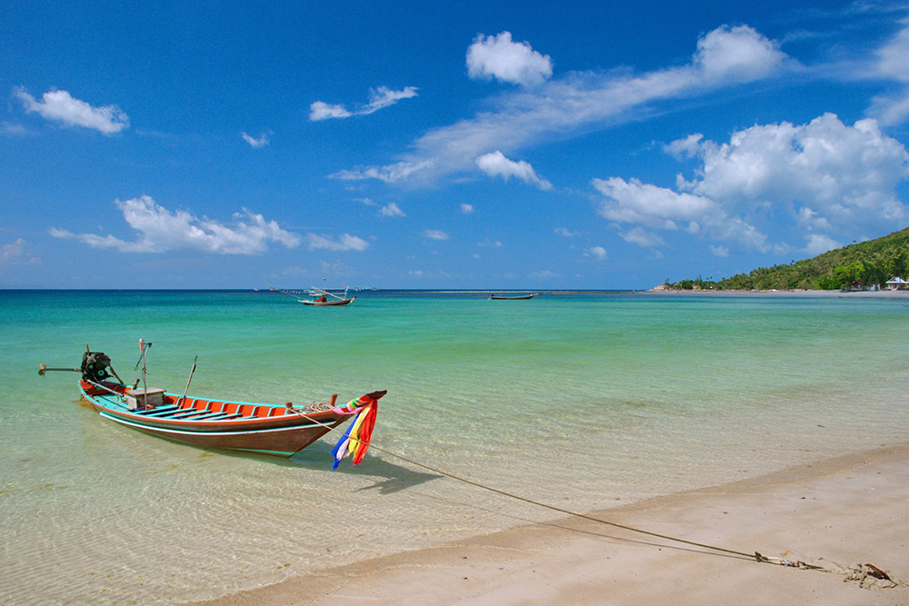 Thailand beach with a traditional boat in clear water, representing the Thailand media campaign case study on Russia-Promo.